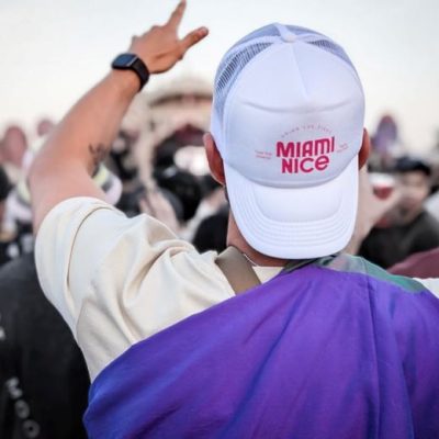 Weiße Trucker-Cap mit pinkem Miami-Nice-Logo auf einem Festival